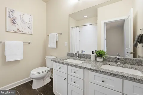 a bathroom with a granite countertop sink mirror vanity and toilet