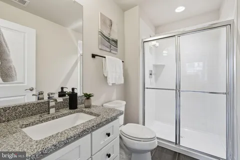 a bathroom with a granite countertop sink mirror vanity and toilet
