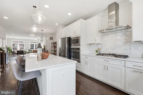 a kitchen with stainless steel appliances granite countertop a sink a stove a refrigerator cabinets and chairs