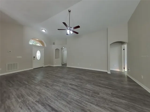a view of an empty room with a ceiling fan and wooden floor