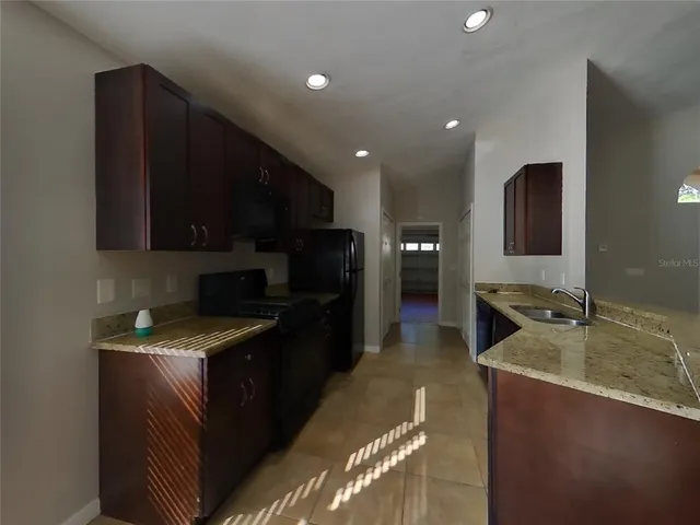 a kitchen with kitchen island granite countertop stainless steel appliances stove microwave refrigerator and sink