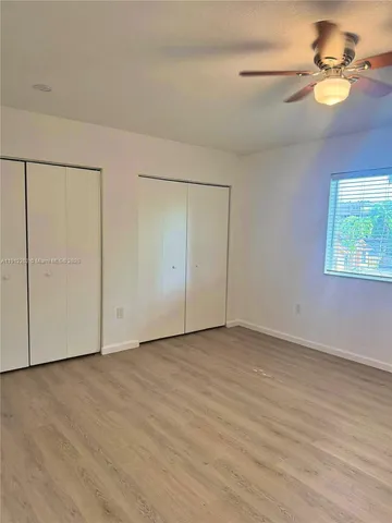 an empty room with windows and fan