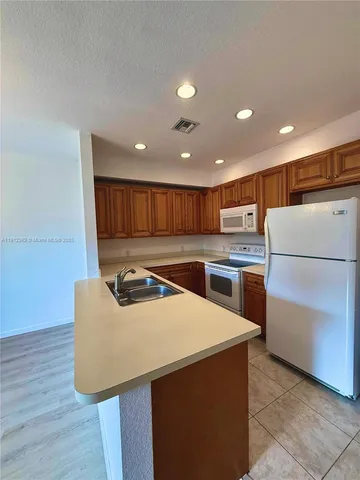 a kitchen with a refrigerator a stove and wooden floor