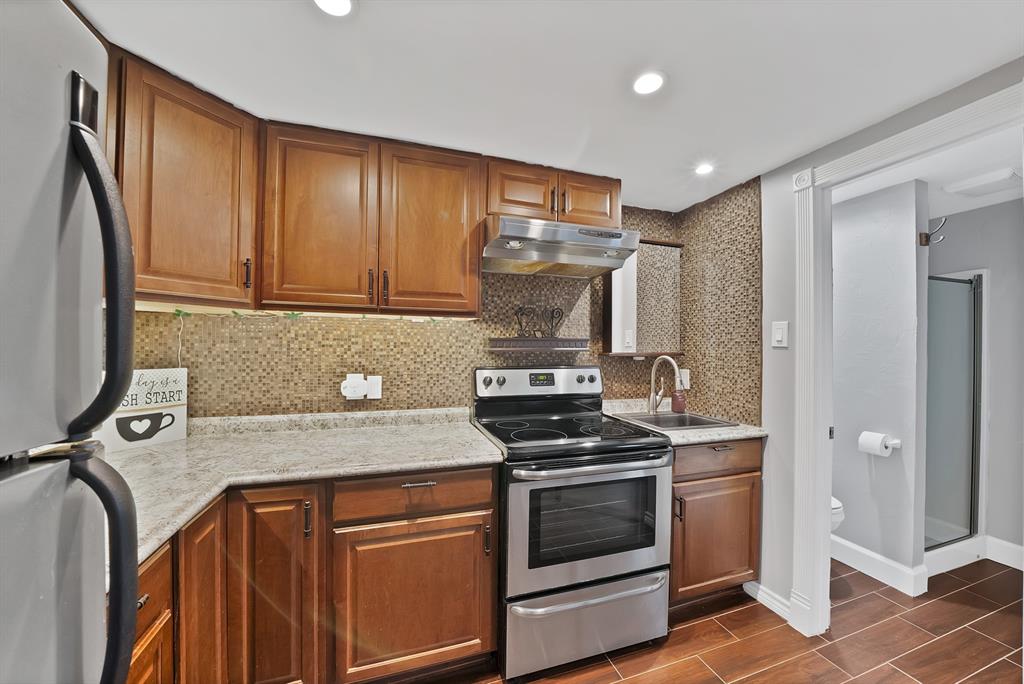 306 Rochelle Boulevard Irving, TX 75062 - Photo 35 of 40 Wood-finish flooring, stainless steel appliances, wood cabinetry, stone-finish countertops, and mosaic tile backsplash