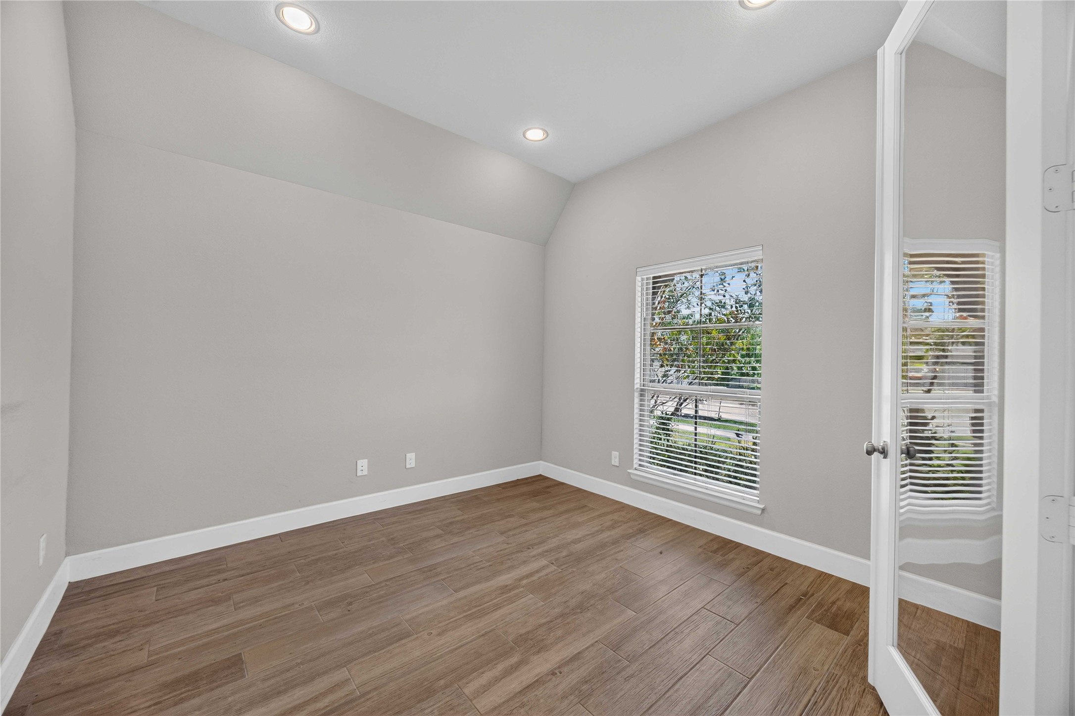 4333 Arbor Crest Lane Manvel, TX 77578 - Photo 4 of 40 Glass-paneled double doors reveal a dedicated, quiet workspace featuring an oversized window, sleek recessed lighting, and warm-toned flooring designed for productivity.