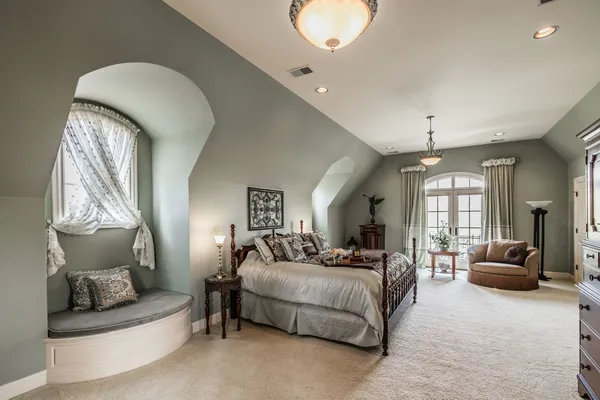 a bedroom with a large bed couch and windows