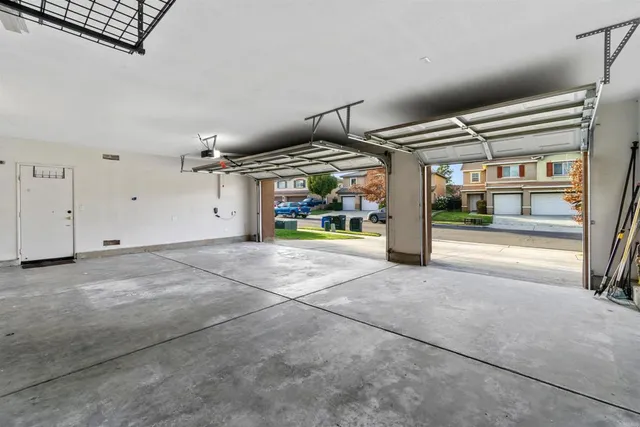 an empty room with chandelier fan and windows