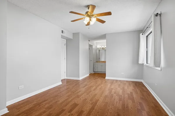 a view of a big room with wooden floor and a chandelier fan in a room