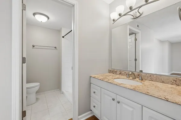a bathroom with a granite countertop sink a toilet and a mirror