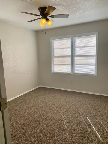 an empty room with a window and chandelier fan