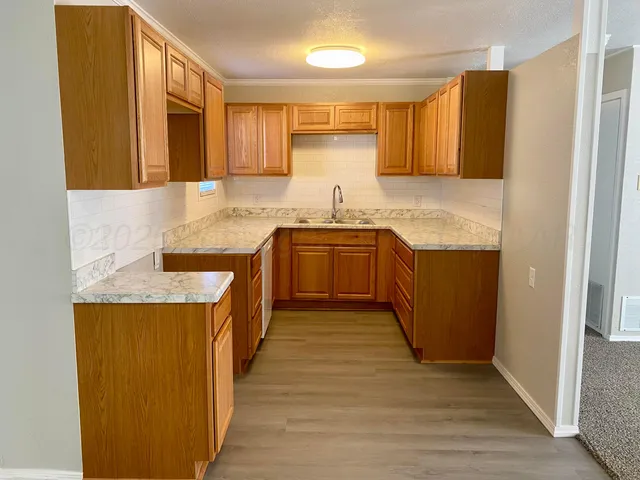 a kitchen with granite countertop a sink cabinets and wooden floor