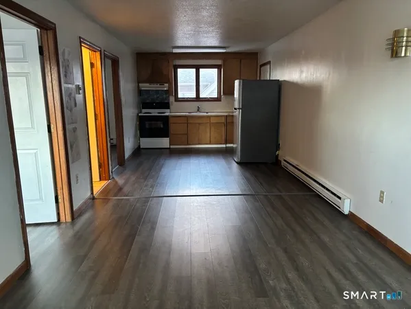 a kitchen with refrigerator and wooden floor