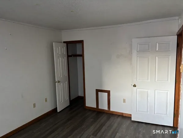 a view of an empty room with wooden floor and closet