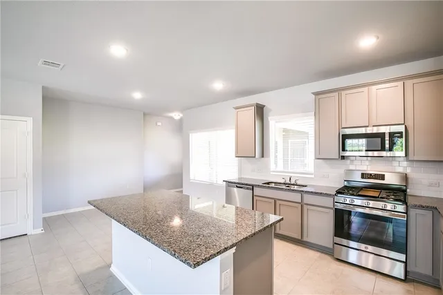a kitchen with stainless steel appliances granite countertop a sink stove and cabinets