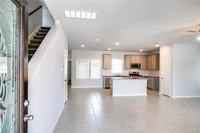 a large white kitchen with stainless steel appliances kitchen island granite countertop a refrigerator and a stove