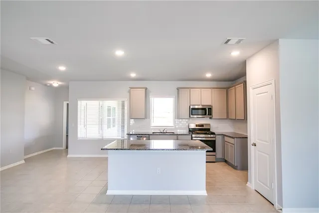 a kitchen with stainless steel appliances granite countertop a stove a sink a refrigerator and white cabinets