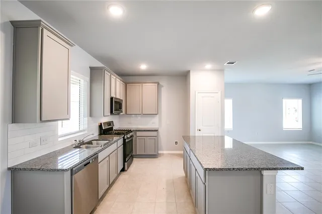 a kitchen with stainless steel appliances granite countertop a sink stove and cabinets