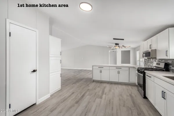 a kitchen with a hard wood floor white cabinets and stainless steel appliances