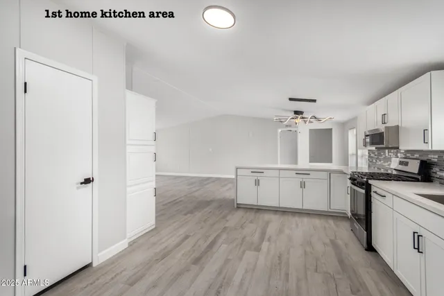 a kitchen with a hard wood floor white cabinets and stainless steel appliances