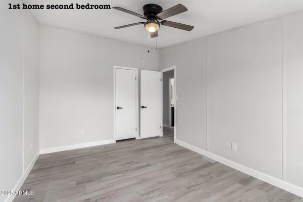 an empty room with wooden floor fan and windows