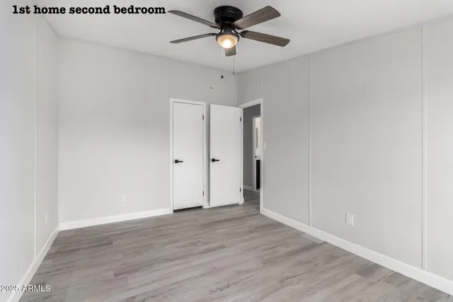 an empty room with wooden floor fan and windows