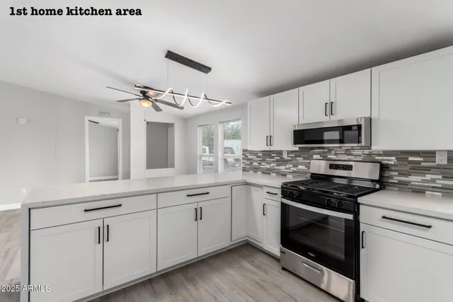 a kitchen with cabinets stainless steel appliances and wooden floor
