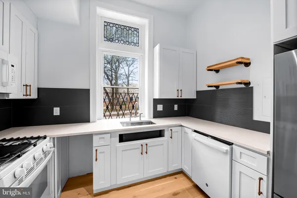 a kitchen with granite countertop a sink dishwasher stove and white cabinets