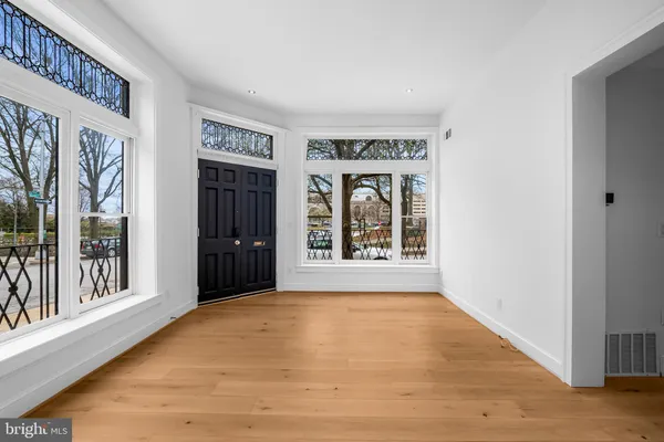 a view of an empty room with large window and wooden floor