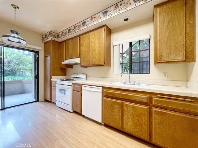 a kitchen with granite countertop a sink cabinets stainless steel appliances and a large window