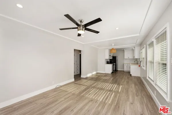a view of a big room with wooden floor a ceiling fan and windows