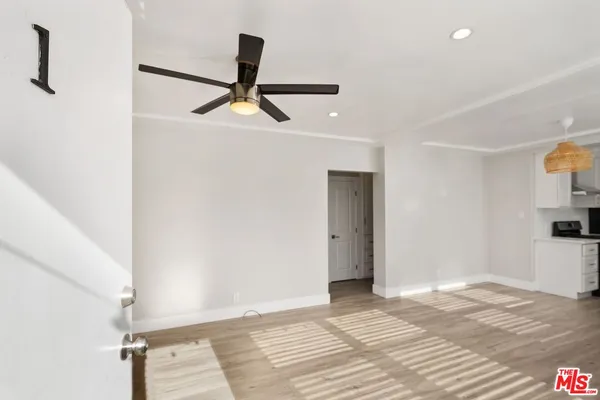 a view of empty room with wooden floor and fan