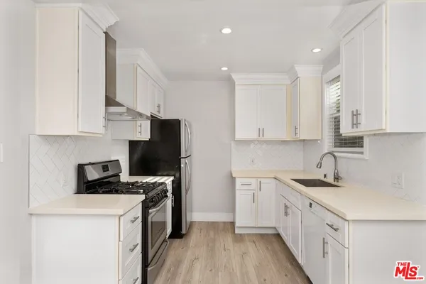 a kitchen with stainless steel appliances granite countertop white cabinets sink and a granite counter top
