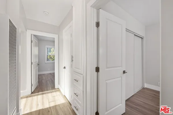 a view of a big room with wooden floor windows and ceiling fan