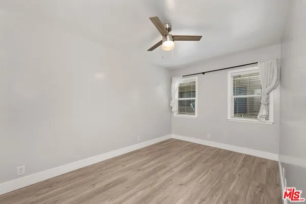 an empty room with wooden floor and ceiling fan