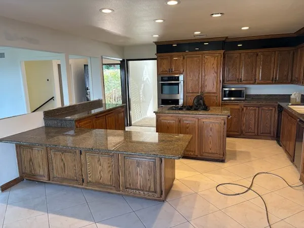 a kitchen with kitchen island granite countertop a stove top oven a sink a counter top space and cabinets