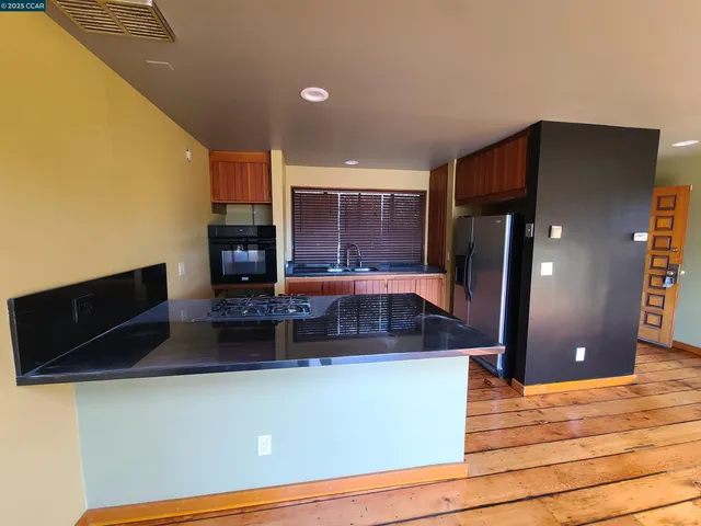 a kitchen with kitchen island granite countertop a refrigerator a stove and a microwave oven