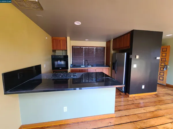 a kitchen with kitchen island granite countertop a refrigerator a stove and a microwave oven