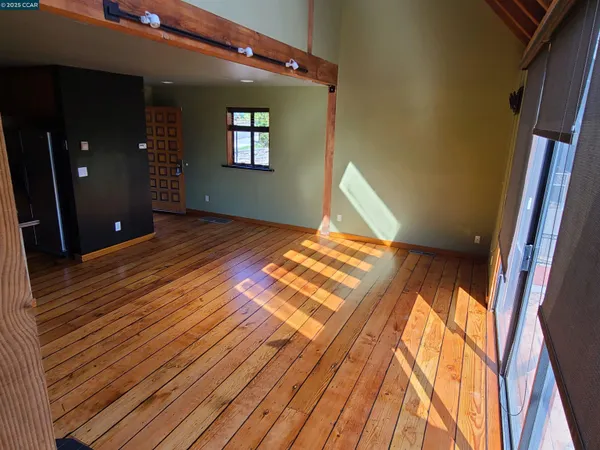 a view of an empty room with wooden floor and a window
