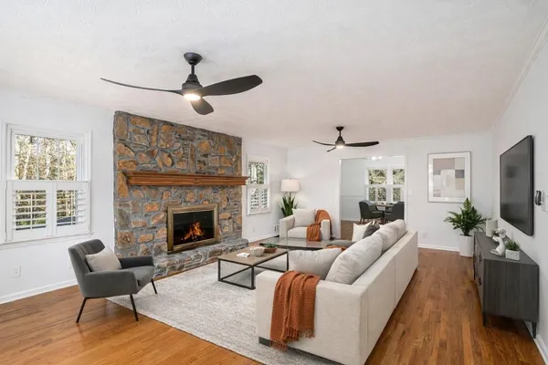 a view of an empty room with wooden floor fireplace and a window