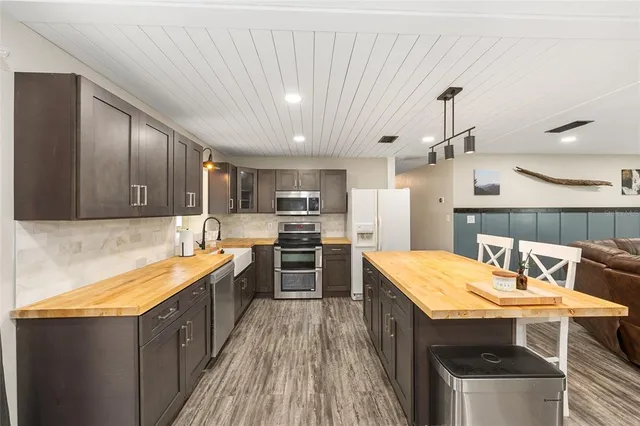 a open kitchen with stainless steel appliances granite countertop a sink dishwasher stove refrigerator and cabinets with wooden floor