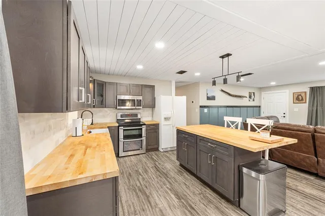 a large kitchen with kitchen island a stove a sink a refrigerator and a wooden cabinets