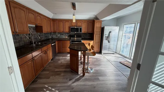 a kitchen with granite countertop a refrigerator a stove top oven a sink and dishwasher