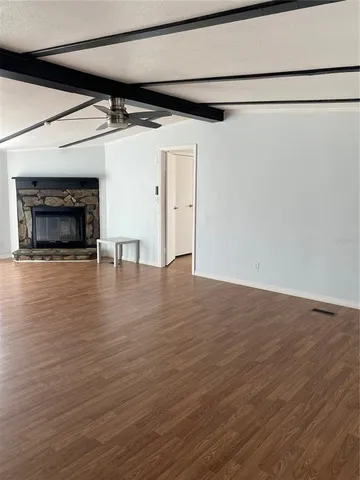 a view of empty room with wooden floor and fireplace