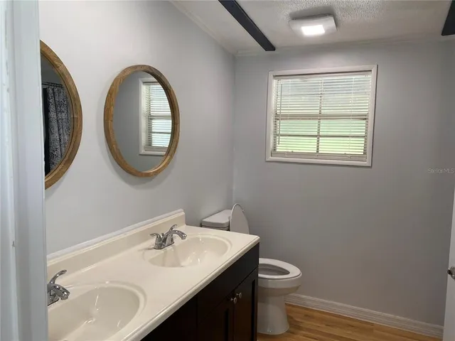 a bathroom with a granite countertop toilet a sink and a mirror