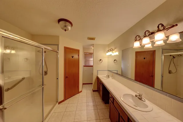 a bathroom with a double vanity sink a large mirror and a shower