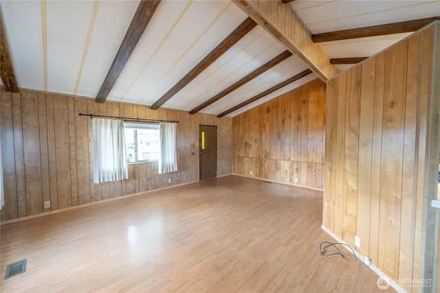 a view of an empty room with wooden floor and windows