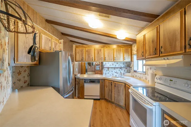 a kitchen with stainless steel appliances granite countertop a refrigerator a sink dishwasher a stove and white cabinets with wooden floor