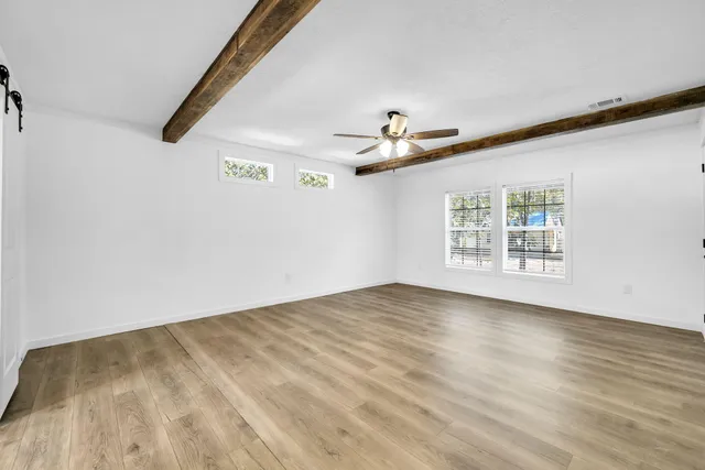 a view of empty room with wooden floor and fan