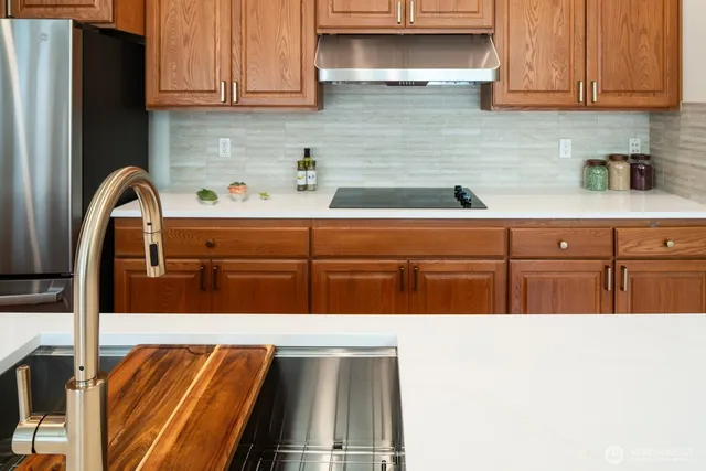 a kitchen with stainless steel appliances wooden cabinets a refrigerator and a sink