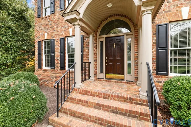 a view of a brick house with large windows and a large tree